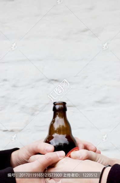 兩只手拿著一個(gè)深色玻璃瓶