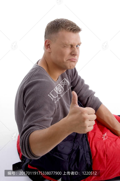 年輕人豎起大拇指和睡袋