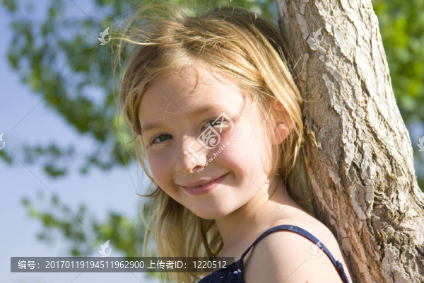 6歲微笑女孩倚著樹
