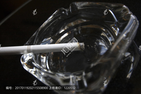 點燃的香煙坐在從端升煙的煙灰缸。黑色和白色的鮮明對比突出了吸煙的嚴峻危險。