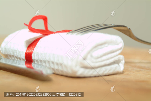 刀和叉著白色的serviertte和紅絲帶