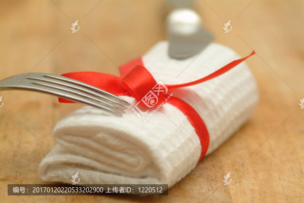 刀和叉著白色的serviertte和紅絲帶
