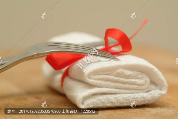 刀和叉著白色的serviertte和紅絲帶