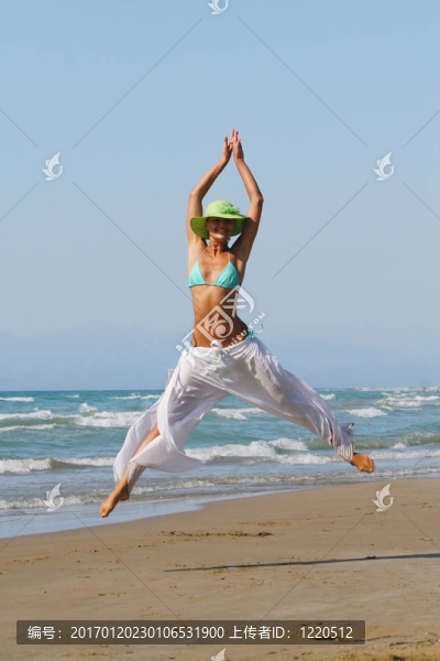 美麗的年輕女子在希臘海灘上跳