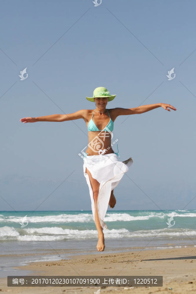 美麗的年輕女子在希臘海灘上跳
