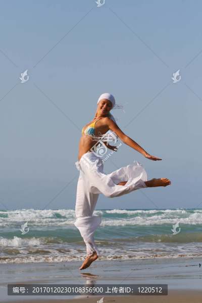 美麗的年輕女子在希臘海灘上跳