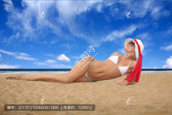 年輕的女人躺在沙灘上曬在白色比基尼
