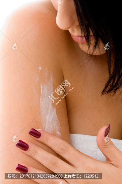 年輕女子在白色背景上涂抹潤膚露