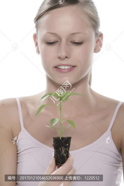 美麗的金發(fā)女孩抱著年輕的植物