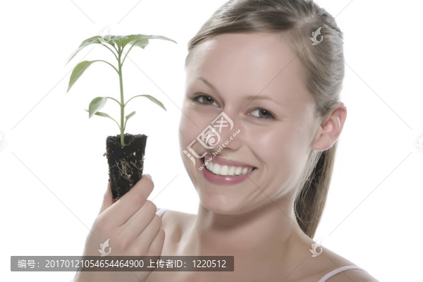 美麗的金發(fā)女孩抱著年輕的植物
