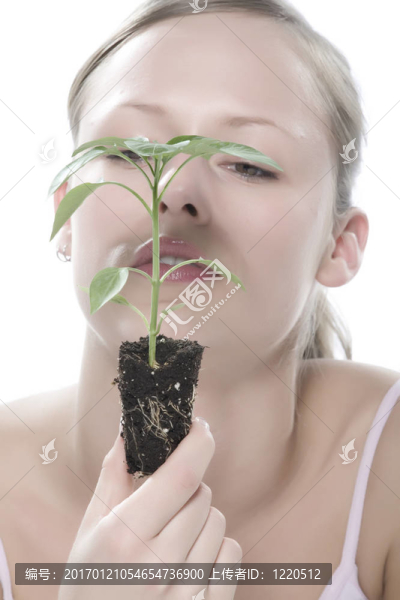 美麗的金發(fā)女孩抱著年輕的植物