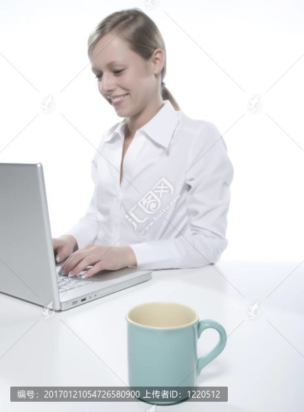 年輕女人看著她的筆記本電腦，喝著咖啡。
