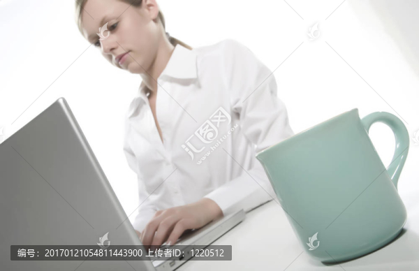 年輕女人看著她的筆記本電腦，喝著咖啡。