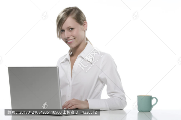 年輕女人看著她的筆記本電腦，喝著咖啡。