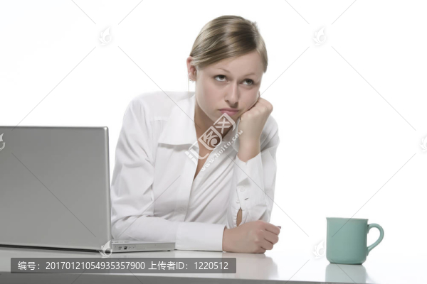 年輕女人看著她的筆記本電腦，喝著咖啡。
