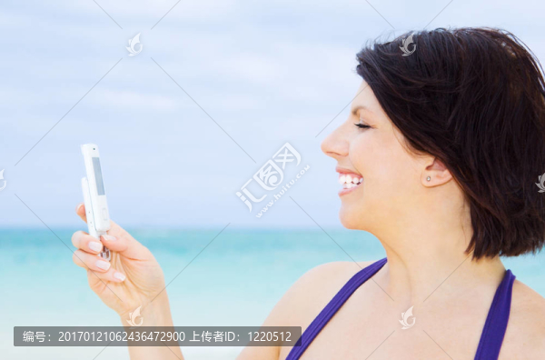 快樂的女人在海灘上的電話