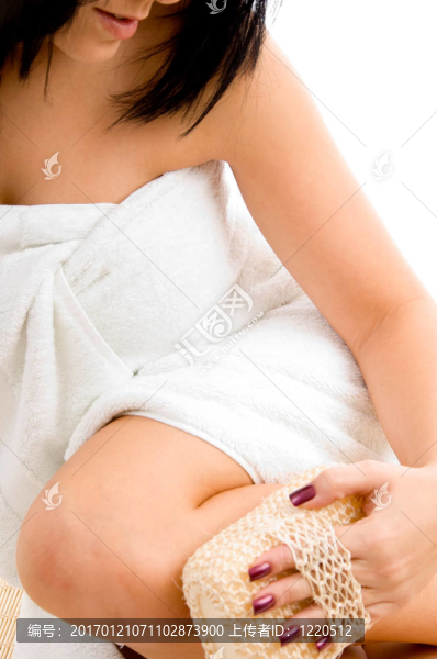 女人用白色背景擦洗她的腿