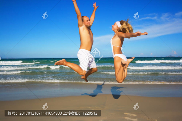 年輕的夫婦在海灘上跳