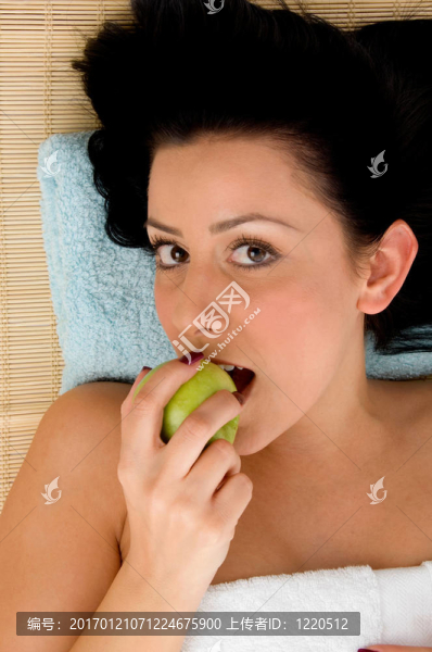 高角度微笑的女人吃蘋果在溫泉