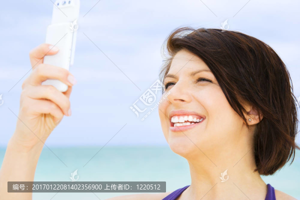 快樂的女人在海灘上的電話