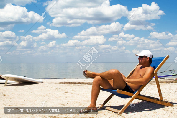 年輕人在海灘上的椅子上對抗海灣和云層