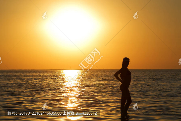 夕陽下海邊的年輕女子剪影
