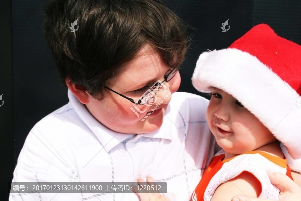大哥哥抱著寶寶戴圣誕帽