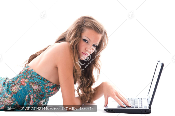 漂亮的女人用筆記本電腦；躺在地板上。