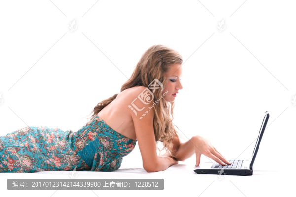 漂亮的女人用筆記本電腦；躺在地板上。