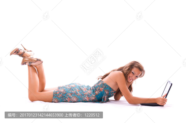 漂亮的女人用筆記本電腦；躺在地板上。