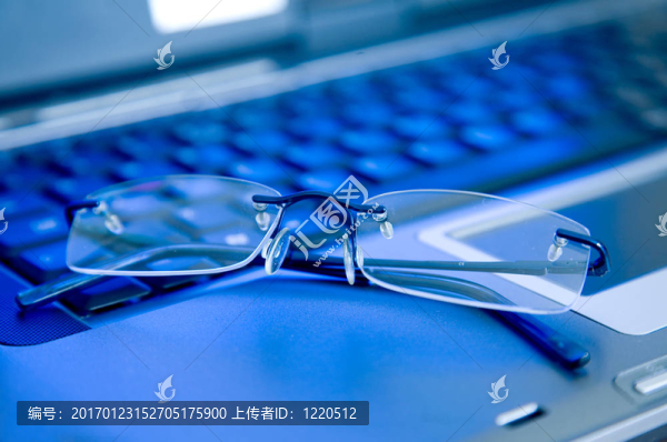 筆記本電腦鍵盤上的商務(wù)眼鏡