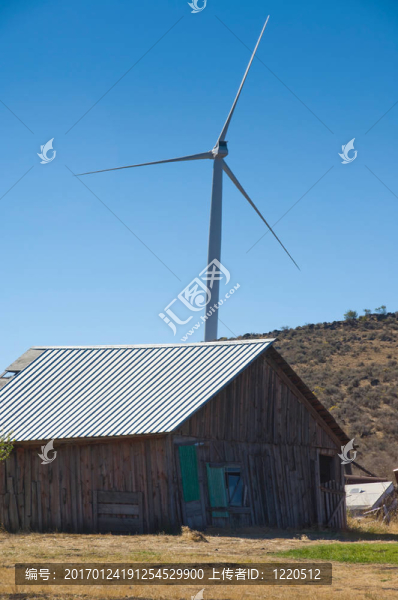 一個農(nóng)場建筑后面的風力渦輪機。