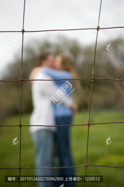 一對夫婦在籬笆后面接吻