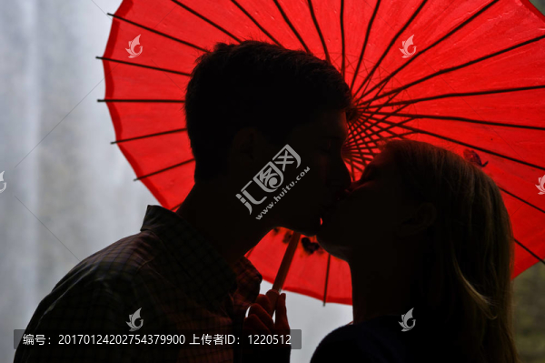 情侶在紅傘前接吻的剪影