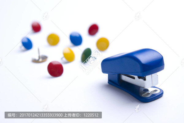 藍(lán)色的訂書機(jī)在白色背景的彩色圖釘。
