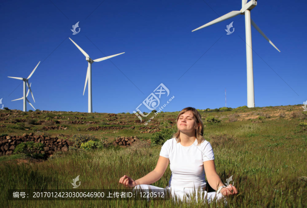年輕的金發(fā)女子做瑜伽對風(fēng)力發(fā)電機的風(fēng)電場下的草