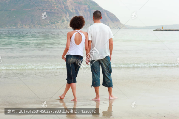 年輕的夫婦在海灘上牽著手