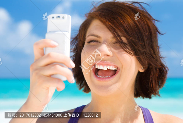 快樂的女人在海灘上的電話