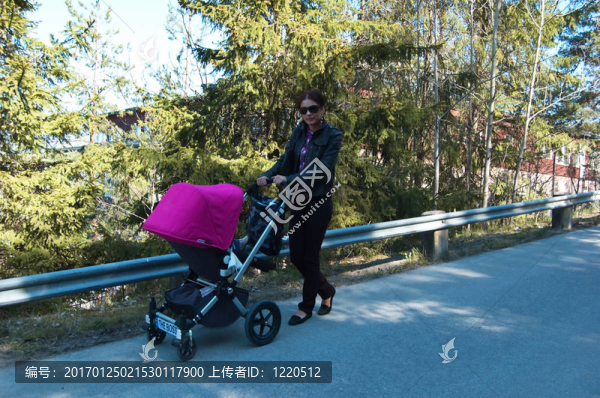 年輕的母親與嬰兒車散步