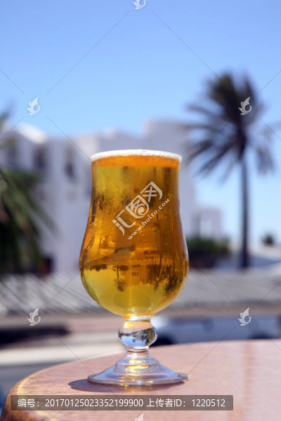反射手掌和藍(lán)天的冰涼啤酒