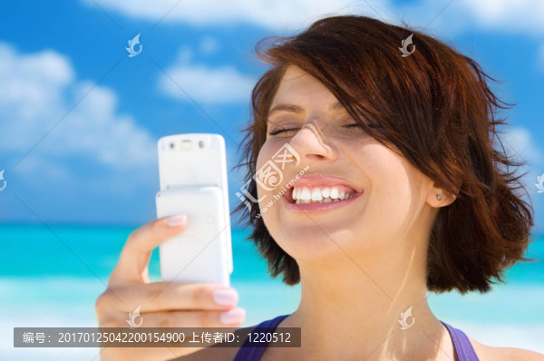 快樂的女人在海灘上的電話