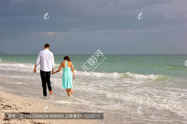 年輕的夫婦沿著海灘的日落背后的美女