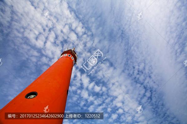 夏日中一座紅色的燈塔對(duì)著多云的藍(lán)天