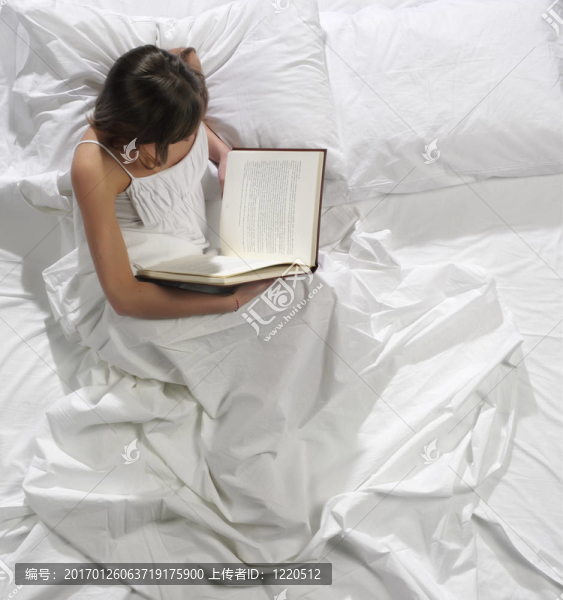 一個漂亮的年輕女人在床上看書