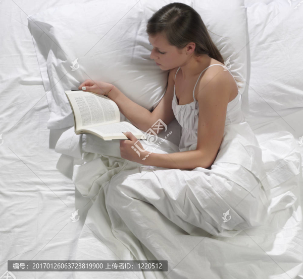 一個(gè)漂亮的年輕女人在床上看書(shū)