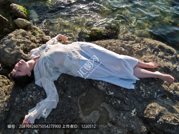 躺在海巖石上的年輕女士的道德禮服