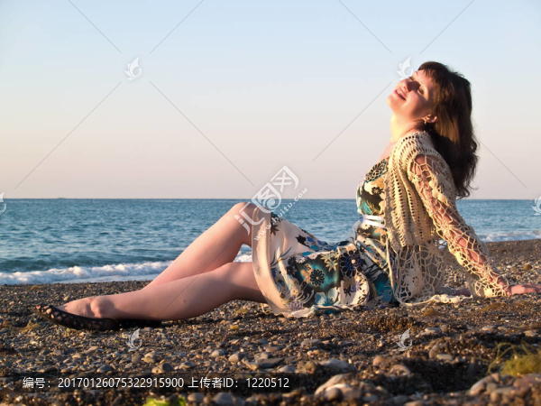 坐在鵝卵石上的美麗的年輕女士