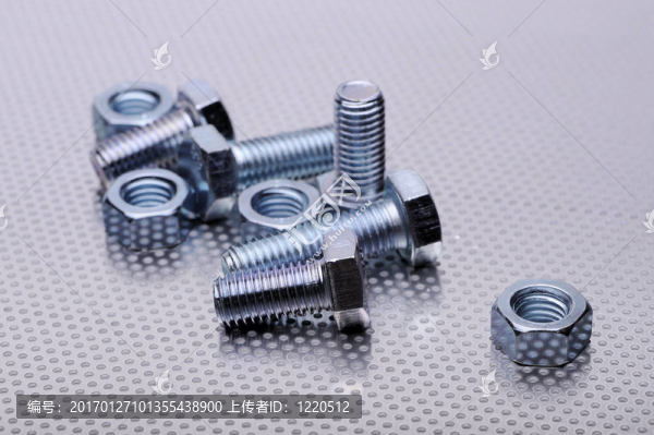穿孔金屬背景上的螺栓和螺母組