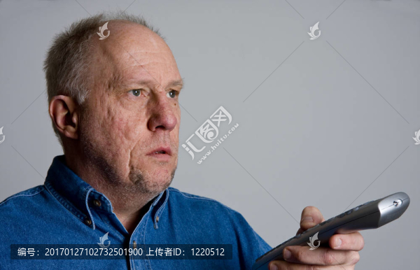 舊的禿頭家伙在藍(lán)色牛仔襯衫遙控