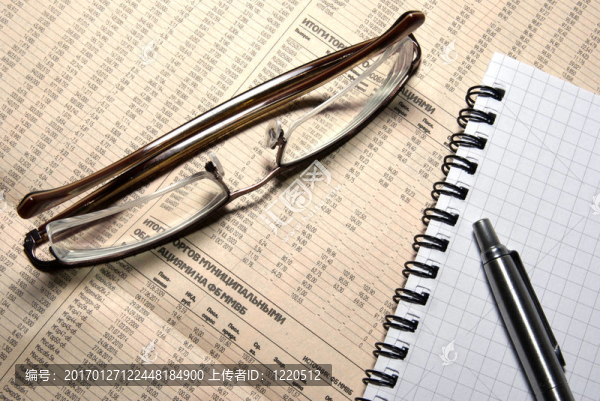 金融數(shù)字報(bào)紙上的筆和筆記本。